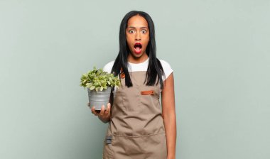 Genç siyahi kadın şok olmuş ya da şaşırmış görünüyor, ağzı açık bir şekilde 