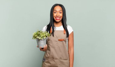 Genç siyahi kadın mutlu ve hoş bir şekilde şaşırmış görünüyor. Büyülenmiş ve şok olmuş bir ifadeyle heyecanlanıyor. Bahçıvan konsepti