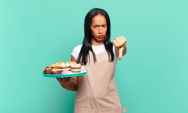 Genç siyahi kadın kızgın, sinirli, hayal kırıklığına uğramış ya da hoşnutsuz hissediyordu. Ciddi bir bakışla baş parmağını aşağı gösteriyordu. Fırın şefi konsepti