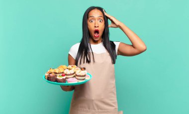 Genç siyah kadın mutlu, şaşkın ve şaşırmış görünüyor, gülümsüyor ve inanılmaz ve inanılmaz iyi haberleri fark ediyor. Fırın şefi konsepti