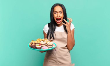 Genç siyahi kadın umutsuz ve sinirli görünüyor, stresli, mutsuz ve sinirli, bağırıyor ve çığlık atıyor. Fırın şefi konsepti