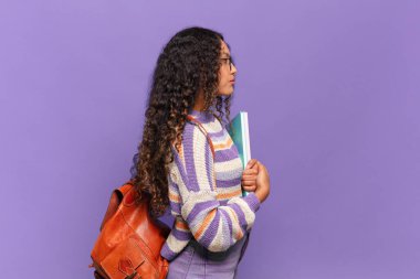 Profil görünümlü genç İspanyol kadın uzayı kopyalamaya çalışıyor, düşünüyor, hayal ediyor ya da hayal kuruyor. öğrenci konsepti