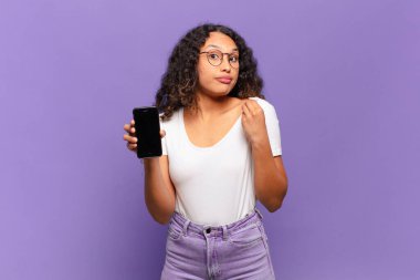 Genç İspanyol kadın kibirli, başarılı, pozitif ve gururlu görünüyor, kendini işaret ediyor. akıllı telefon kavramı