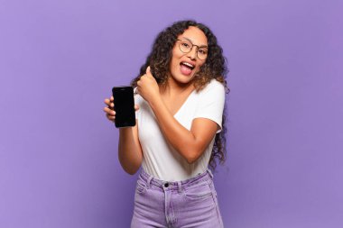 Genç İspanyol kadın mutlu, pozitif ve başarılı hissediyor, bir meydan okumayla karşılaştığında ya da iyi sonuçları kutladığında motive oluyor. akıllı telefon kavramı