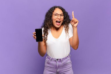 Genç İspanyol kadın bir fikri fark ettikten sonra mutlu ve heyecanlı bir dahi gibi hissediyor, neşeli bir şekilde parmağını kaldırıyor, eureka! akıllı telefon kavramı