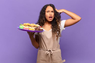 Genç İspanyol kadın mutlu, şaşkın ve şaşırmış görünüyor, gülümsüyor ve inanılmaz ve inanılmaz iyi haberleri fark ediyor. kek pişirme kavramı