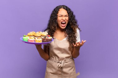 Genç İspanyol bir kadın kızgın, sinirli ve sinirli görünüyor. Senin neyin var, neyin yok? kek pişirme kavramı 