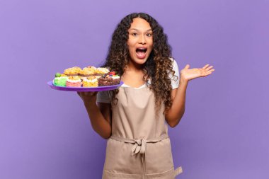 Genç İspanyol kadın mutlu, şaşırmış ve neşeli hissediyor, olumlu bir tavırla gülümsüyor, bir çözüm ya da fikrin farkına varıyor. kek pişirme kavramı