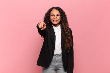 Genç İspanyol kadın kameraya tatmin olmuş, kendine güvenen, dost canlısı bir gülümsemeyle bakıyor ve seni seçiyor. iş kavramı