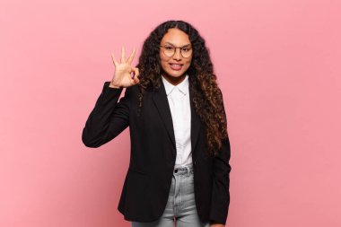 Genç İspanyol kadın kendini mutlu, rahat ve tatmin olmuş hissediyor. İyi bir jestle onaylıyor, gülümsüyor. iş kavramı