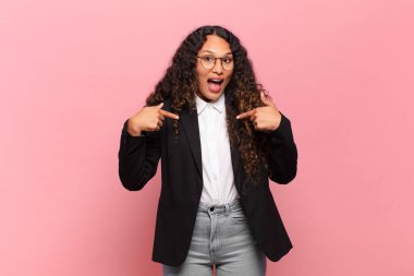 Genç İspanyol kadın mutlu, şaşkın ve gururlu hissediyor. Heyecanlı ve şaşkın bakışlarıyla kendini işaret ediyor. iş kavramı