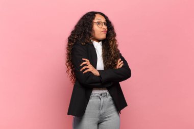 Genç İspanyol kadın omuz silkiyor, kafası karışık ve emin değil, kolları bağlı ve şaşkın görünüyor. iş kavramı