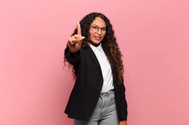 Genç İspanyol kadın gururla gülümsüyor ve gururla bir numaralı pozunu veriyor, kendini lider gibi hissediyor. iş kavramı