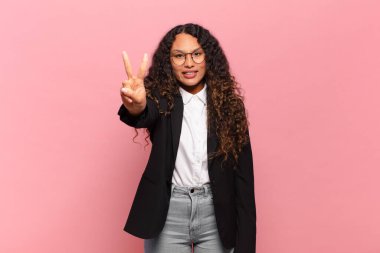 Genç İspanyol kadın gülümsüyor ve arkadaş canlısı görünüyor. İki ya da iki numarayı gösteriyor. Elleri önde, geriye doğru sayıyor. iş kavramı