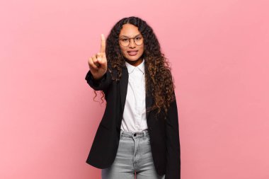 Genç İspanyol kadın gülümsüyor ve arkadaş canlısı görünüyor, bir numara ya da ilk eli önde, geriye doğru sayıyor. iş kavramı