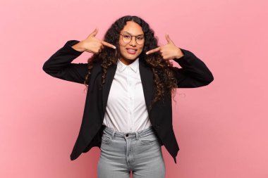 Genç İspanyol kadın kendine güvenerek gülümsüyor. Geniş gülümseme, pozitif, rahat, tatmin olmuş tavır. iş kavramı