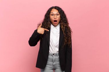 Genç İspanyol kadın şok olmuş ve ağzı açık, kendini işaret ederek şaşırmış görünüyor. iş kavramı