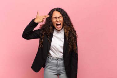 Genç İspanyol kadın mutsuz ve stresli görünüyor, intihar jesti elle silah işareti yapıyor, kafasını işaret ediyor. iş kavramı