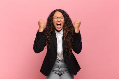 Genç İspanyol kadın öfkeli bir ifadeyle agresif bir şekilde bağırıyor ya da yumruklarıyla başarıyı kutluyor. iş kavramı