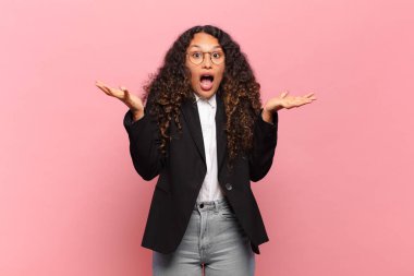 Genç İspanyol kadın aşırı derecede şok olmuş ve şaşırmış, endişeli ve paniklemiş hissediyor, stresli ve dehşete kapılmış bir bakışla. iş kavramı