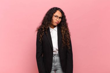 young hispanic woman feeling puzzled and confused, with a dumb, stunned expression looking at something unexpected. business concept