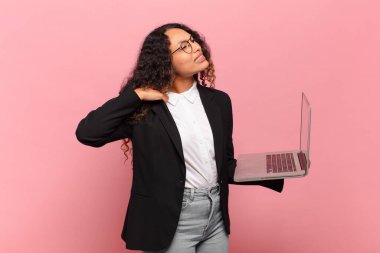 Genç İspanyol kadın stresli, endişeli, yorgun ve hayal kırıklığına uğramış, gömleğini çekmiş, sorunlu görünüyor. dizüstü bilgisayar