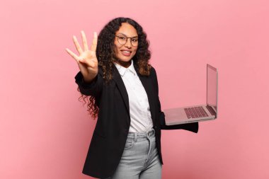 Genç İspanyol kadın gülümsüyor ve arkadaş canlısı görünüyor. Dört ya da dört numarayı gösteriyor. Elleri önde, geriye doğru sayıyor. dizüstü bilgisayar