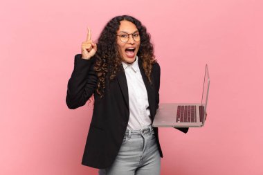 Genç İspanyol kadın bir fikri fark ettikten sonra mutlu ve heyecanlı bir dahi gibi hissediyor, neşeli bir şekilde parmağını kaldırıyor, eureka! dizüstü bilgisayar