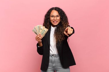 Genç İspanyol kadın kameraya tatmin olmuş, kendine güvenen, dost canlısı bir gülümsemeyle bakıyor ve seni seçiyor. Dolar banknotları konsepti