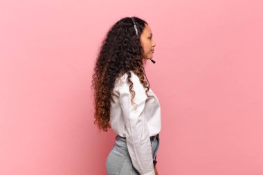 Profil görünümlü genç İspanyol kadın uzayı kopyalamaya çalışıyor, düşünüyor, hayal ediyor ya da hayal kuruyor. tele pazarlamacı kavramı