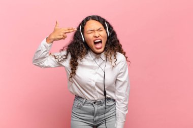 Genç İspanyol kadın mutsuz ve stresli görünüyor, intihar jesti elle silah işareti yapıyor, kafasını işaret ediyor. tele pazarlamacı kavramı