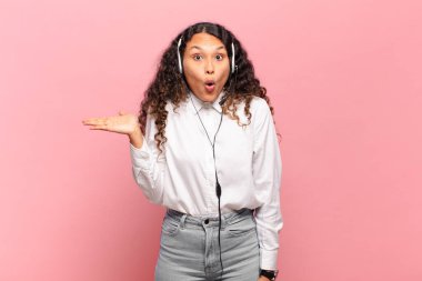 Genç İspanyol kadın şaşırmış ve şok olmuş görünüyor. Çenesi düşmüş ve eli açık bir objeyi tutuyor. tele pazarlamacı kavramı