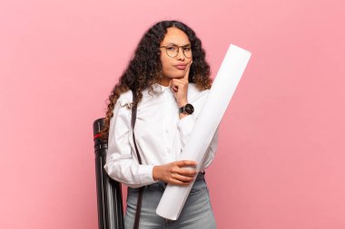 Genç İspanyol kadın mutlu bir şekilde gülümsüyor ve hayal kuruyor ya da şüphe ediyor, yana bakıyor. mimar konsepti