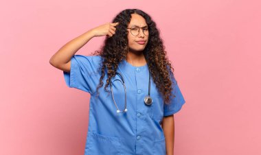 Genç İspanyol kadın şaşkın ve şaşkın hissediyor. Deli, deli ya da aklını kaçırmış olduğunu gösteriyor. hemşire konsepti