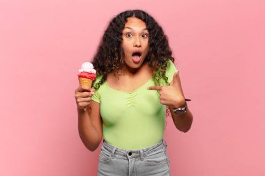 Genç İspanyol kadın şok olmuş ve ağzı açık, kendini işaret ederek şaşırmış görünüyor. dondurma konsepti