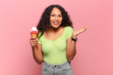 Genç İspanyol kadın mutlu, şaşırmış ve neşeli hissediyor, olumlu bir tavırla gülümsüyor, bir çözüm ya da fikrin farkına varıyor. dondurma konsepti