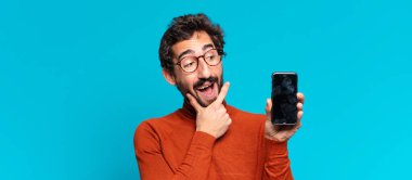 Genç, deli, sakallı adam. Düşünen ya da şüphe eden bir ifade. akıllı telefon kavramı