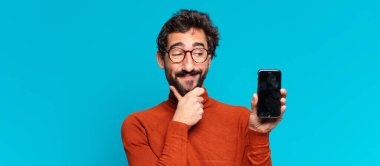 Genç, deli, sakallı adam. Düşünen ya da şüphe eden bir ifade. akıllı telefon kavramı