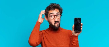 Genç, deli, sakallı adam. Düşünen ya da şüphe eden bir ifade. akıllı telefon kavramı