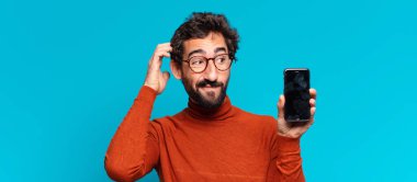 Genç, deli, sakallı adam. Düşünen ya da şüphe eden bir ifade. akıllı telefon kavramı