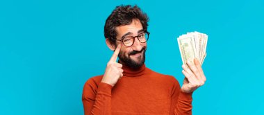 Genç, deli, sakallı adam. Düşünen ya da şüphe eden bir ifade. Dolar banknotları konsepti