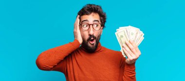 Genç, deli, sakallı adam. Şaşırmış ya da şok olmuş. Dolar banknotları konsepti