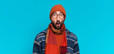 Genç, deli, sakallı adam. Şok olmuş ya da şaşırmış bir ifade ve kışlık kıyafetler.