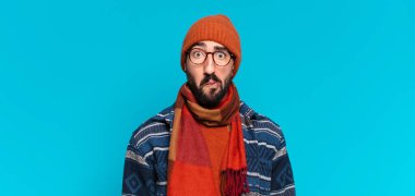 Genç, deli, sakallı adam. Şok olmuş ya da şaşırmış bir ifade ve kışlık kıyafetler.