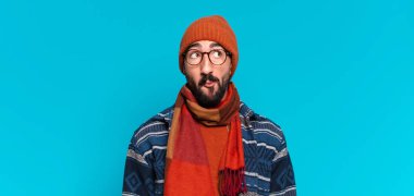 Genç, deli, sakallı adam. Şok olmuş ya da şaşırmış bir ifade ve kışlık kıyafetler.