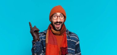 Genç, deli, sakallı adam. Şok olmuş ya da şaşırmış bir ifade ve kışlık kıyafetler.