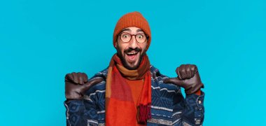 Genç çılgın sakallı adam gururlu bir ifade ve kışlık kıyafetler giyiyor.