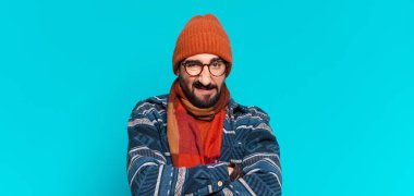 Genç, çılgın sakallı, kızgın bir adam ifadesi ve kışlık kıyafetler giyiyor.