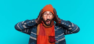 Genç, deli, sakallı adam. Şok olmuş ya da şaşırmış bir ifade ve kışlık kıyafetler.