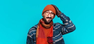 Genç çılgın sakallı adam üzgün bir ifade ve kışlık kıyafetler giyiyor.